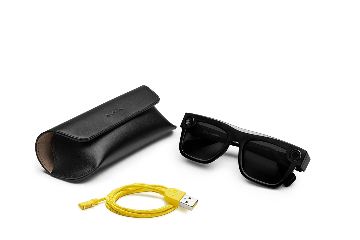 Black Spectacles, carrying case, and yellow charging cable.