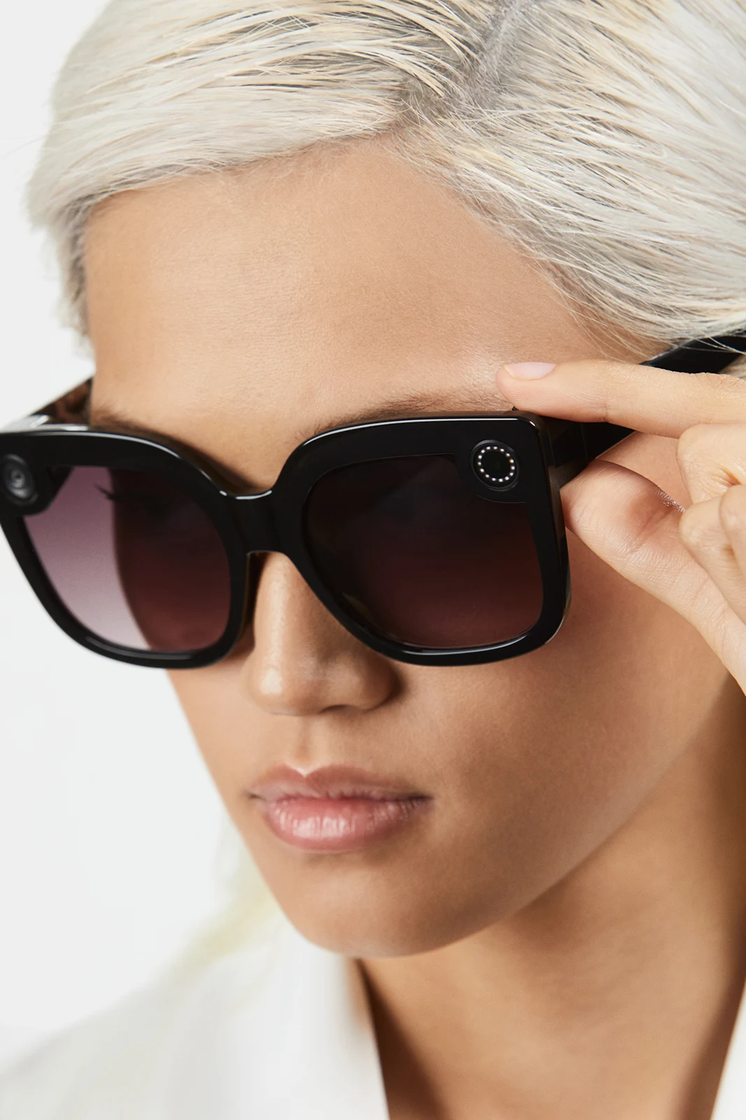 Close-up of a model adjusting a rounded black Spectacles frame.