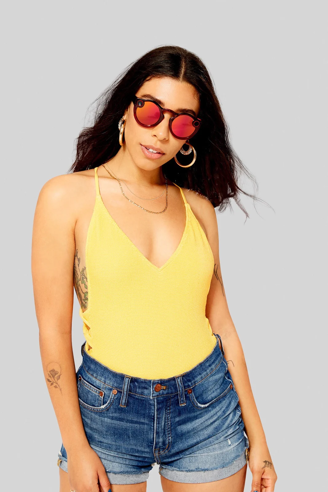 Studio portrait in a yellow top and red mirrored Spectacles.