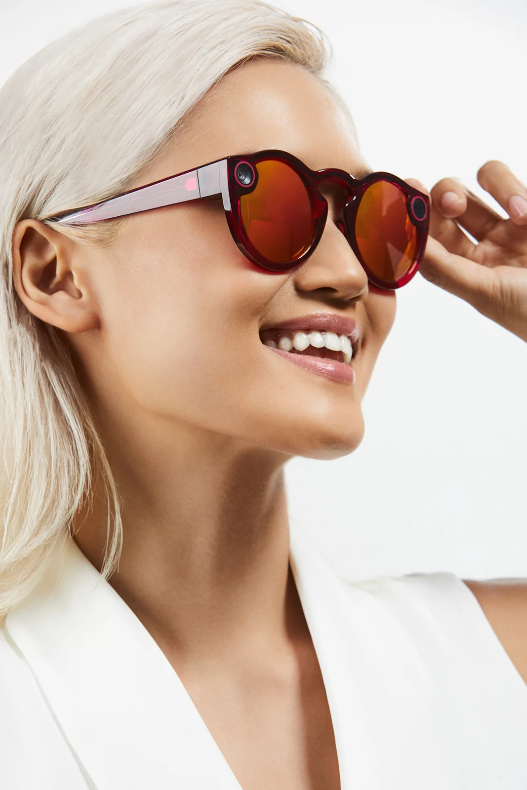 Model lifting red mirrored Spectacles toward the light.