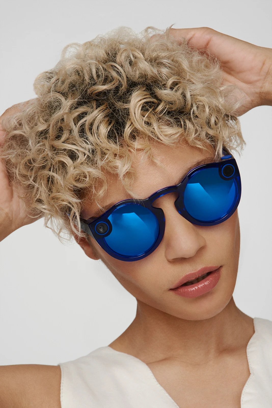 Portrait of a curly-haired model wearing blue mirrored Spectacles.