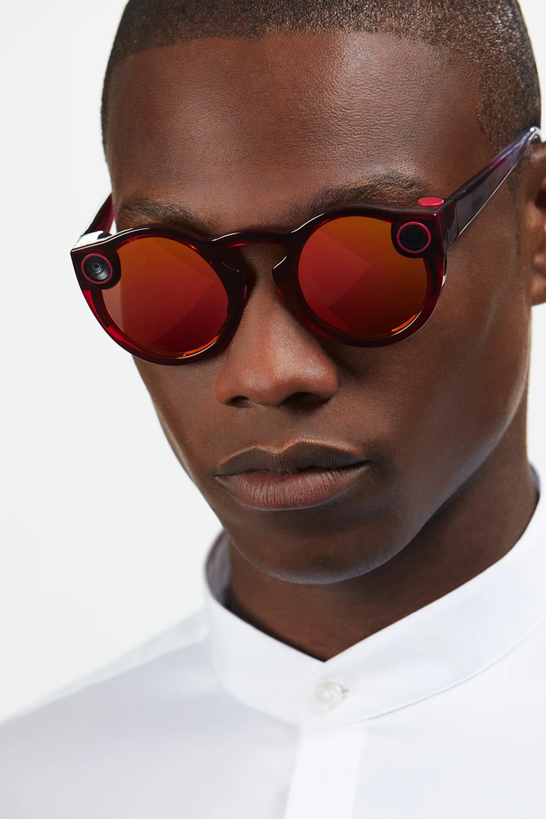 Front-facing studio portrait in red mirrored Spectacles.