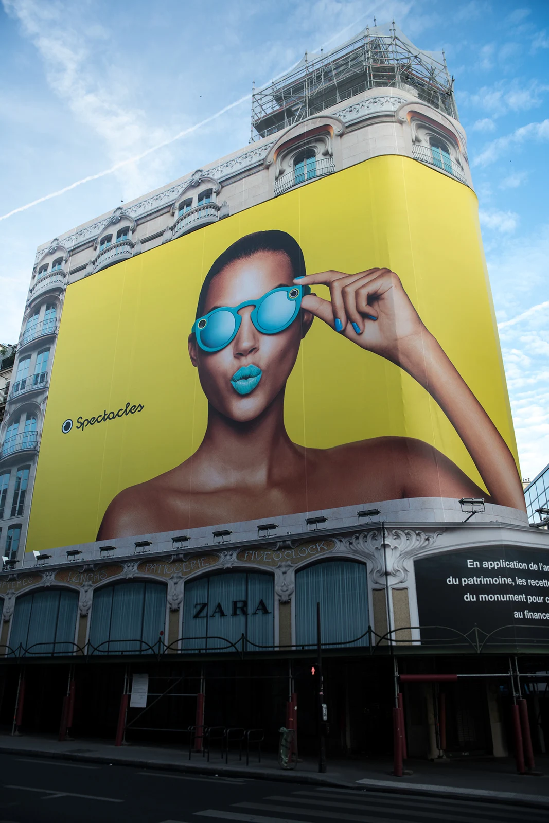 Large Spectacles portrait displayed on a curved city billboard.