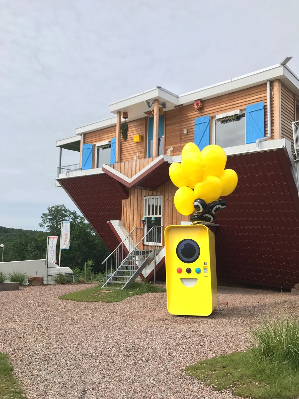Yellow Snapbot vending machine and balloons outside a house.