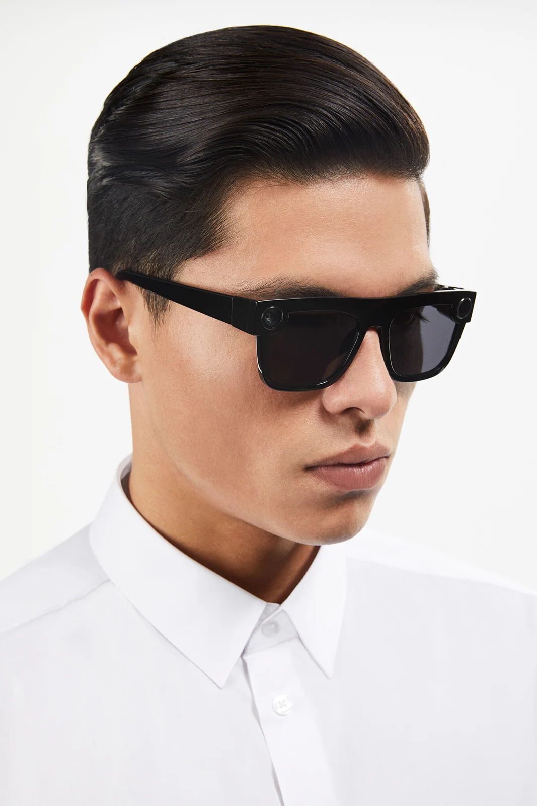 Studio portrait of a model in angular black Spectacles and a white shirt.