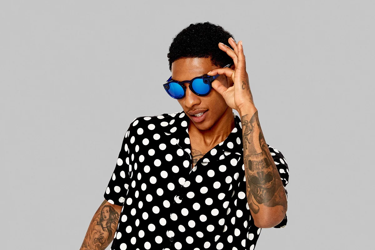 Studio portrait in a polka-dot shirt and blue mirrored Spectacles.