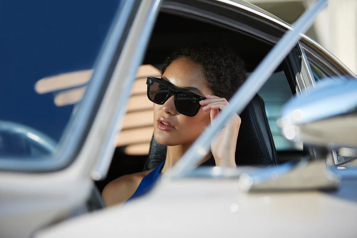 Model wearing black Spectacles, framed through a car window.