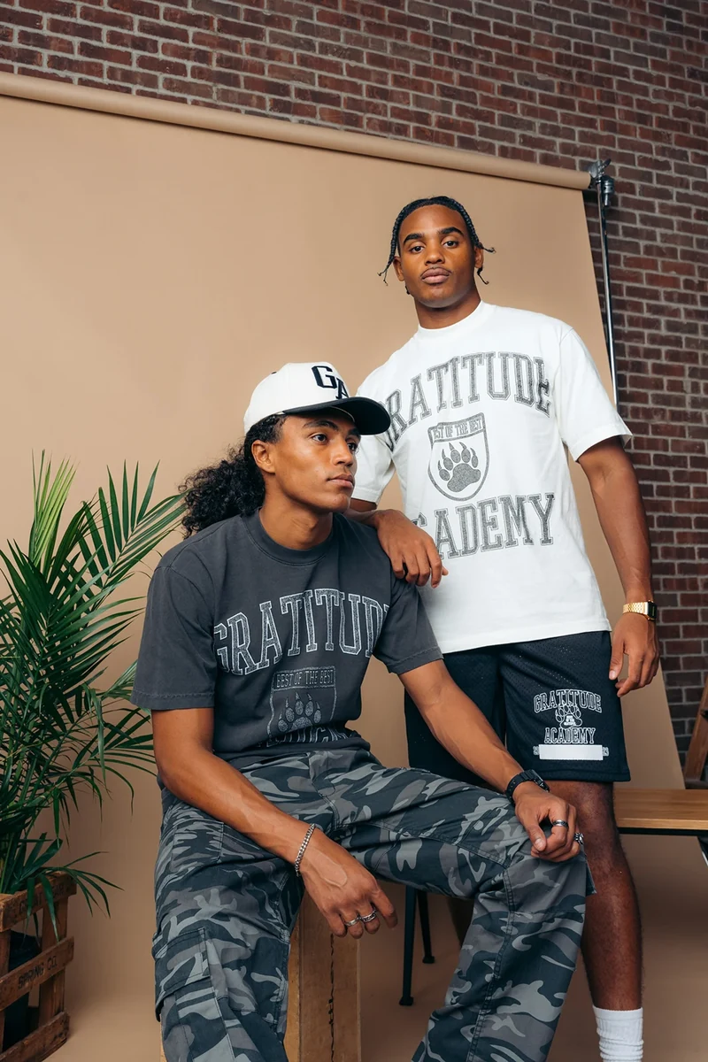 Two models wearing black and white Gratitude Academy tees.