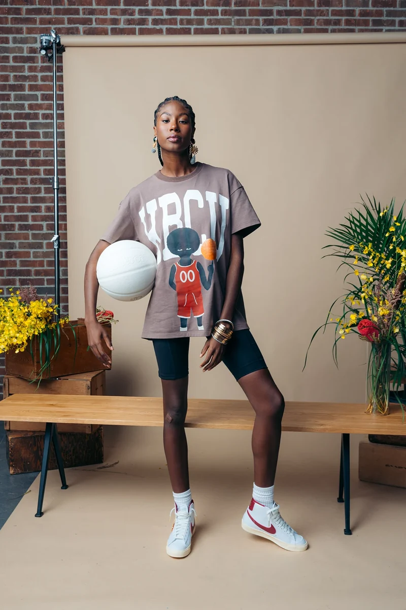 Model holding a white basketball beside the studio bench.
