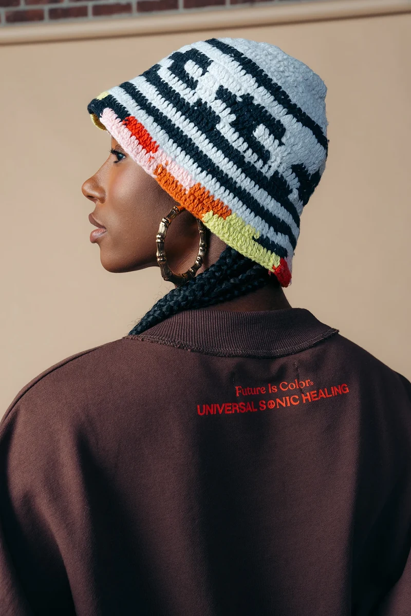 Profile portrait showing a striped knit hat and embroidered tee detail.
