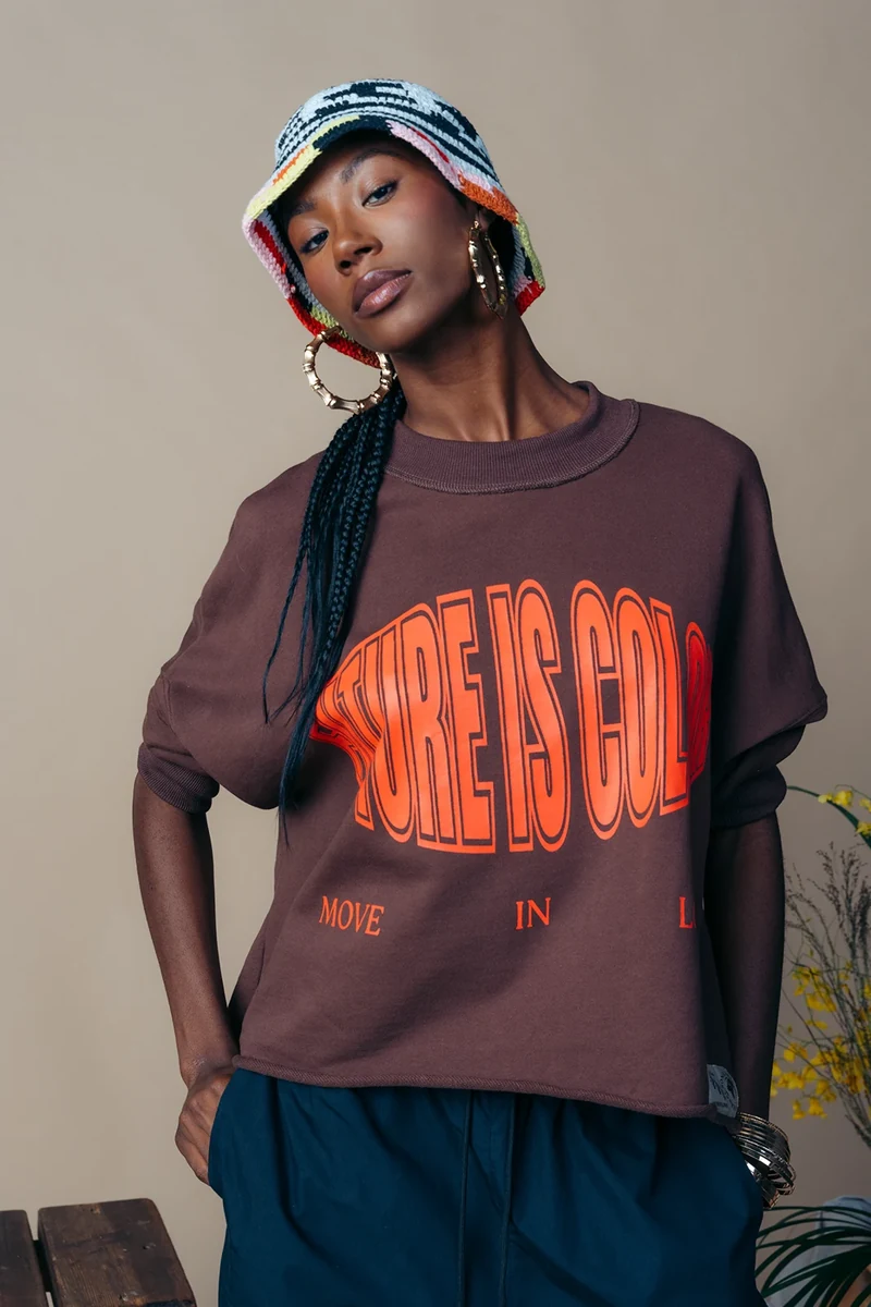 Portrait of a model in a brown graphic tee and striped knit hat.