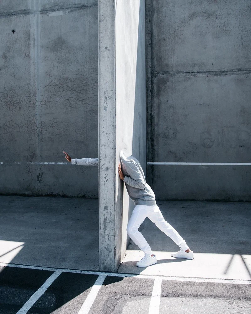 Wide composition with a model leaning around a tall concrete column.