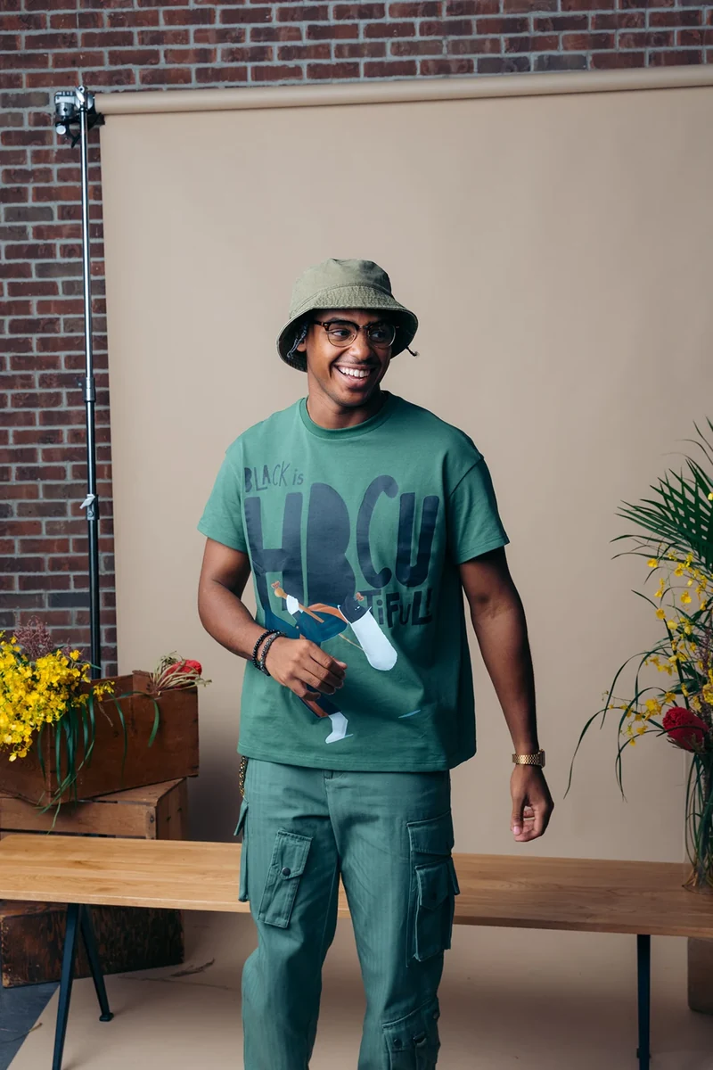 Model wearing a green graphic tee, cargo trousers, and bucket hat.