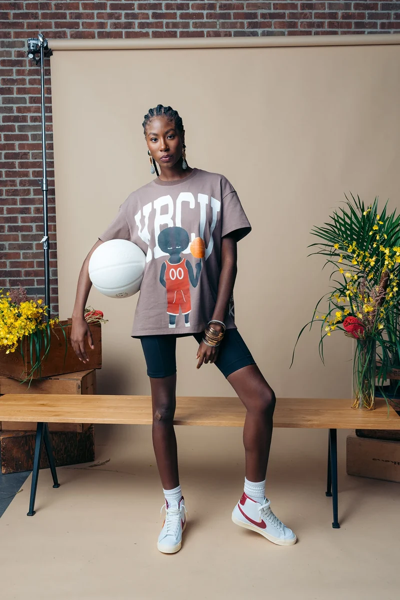 Full-length portrait of a model in a graphic tee and black cycling shorts.