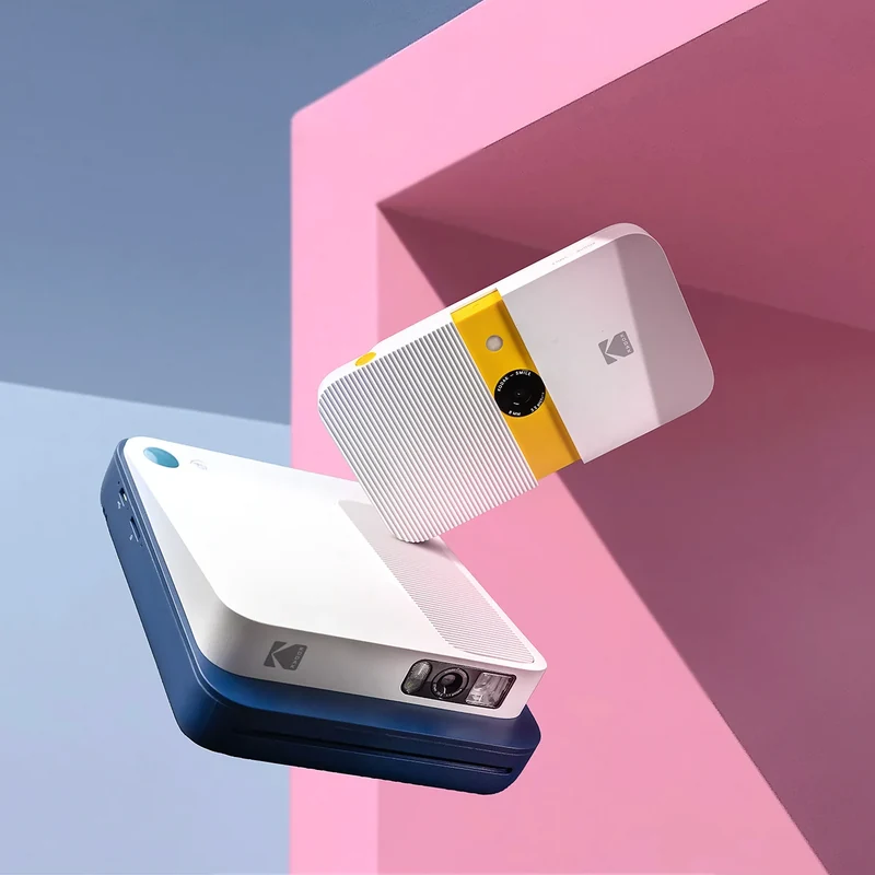 Kodak cameras arranged against blue and pink geometric backgrounds.