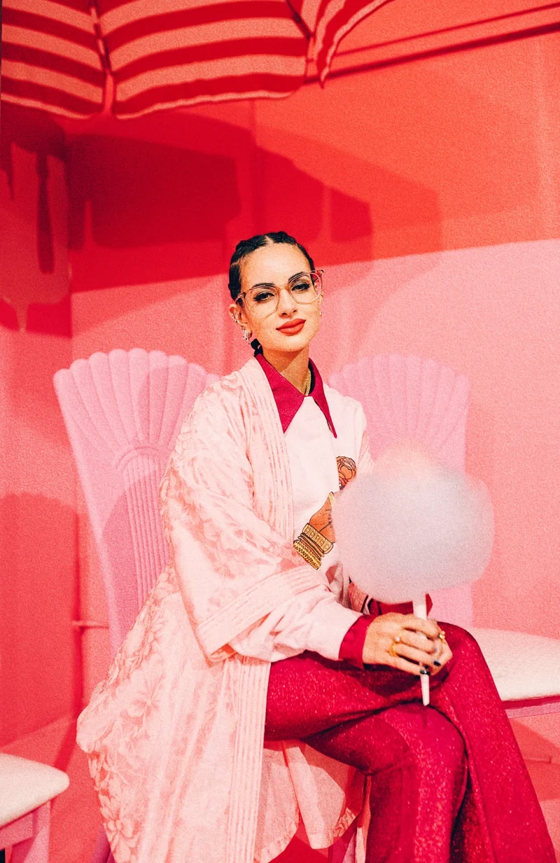 Seated portrait holding cotton candy against the coral wall.