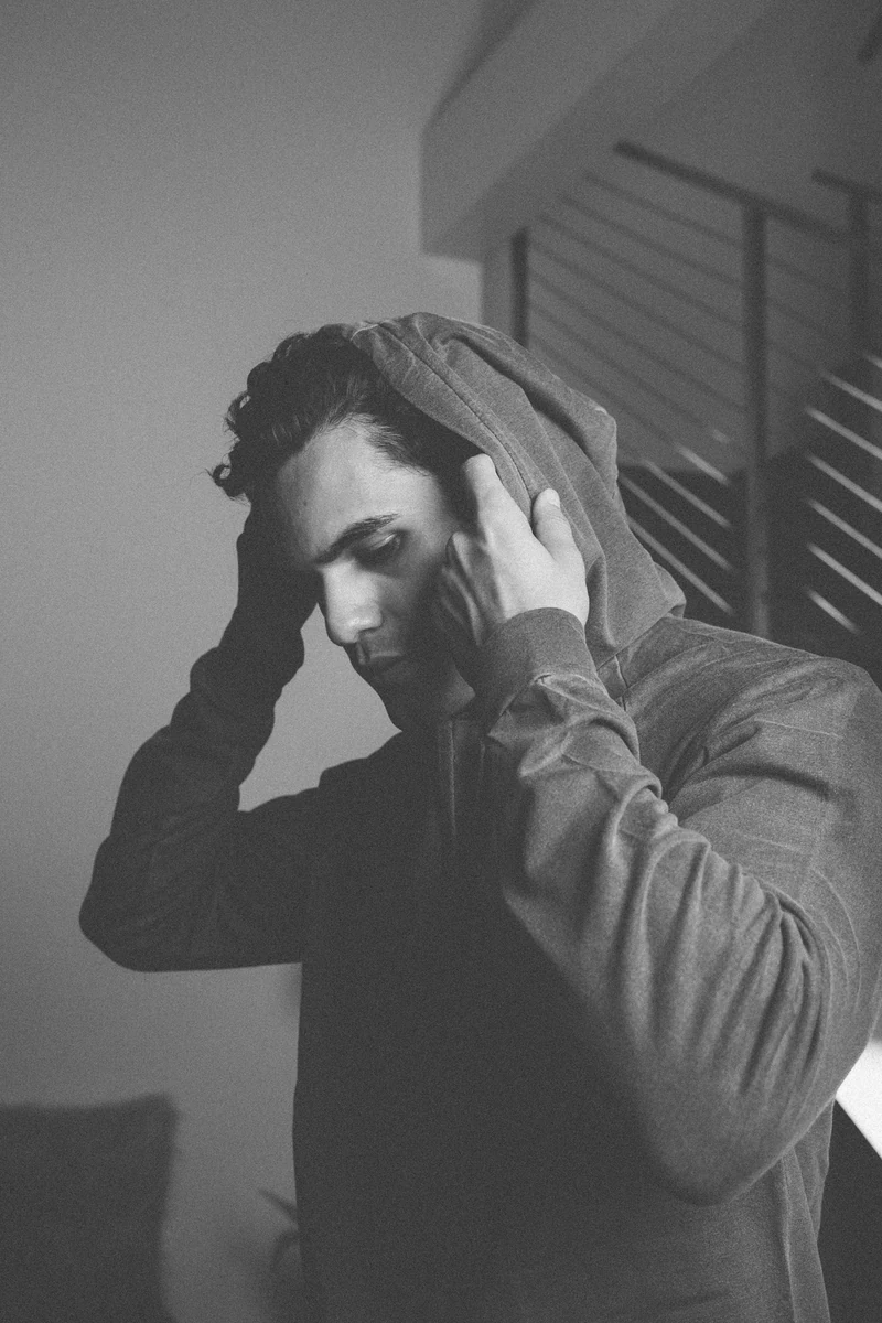 Monochrome portrait of a model adjusting a sweatshirt hood.