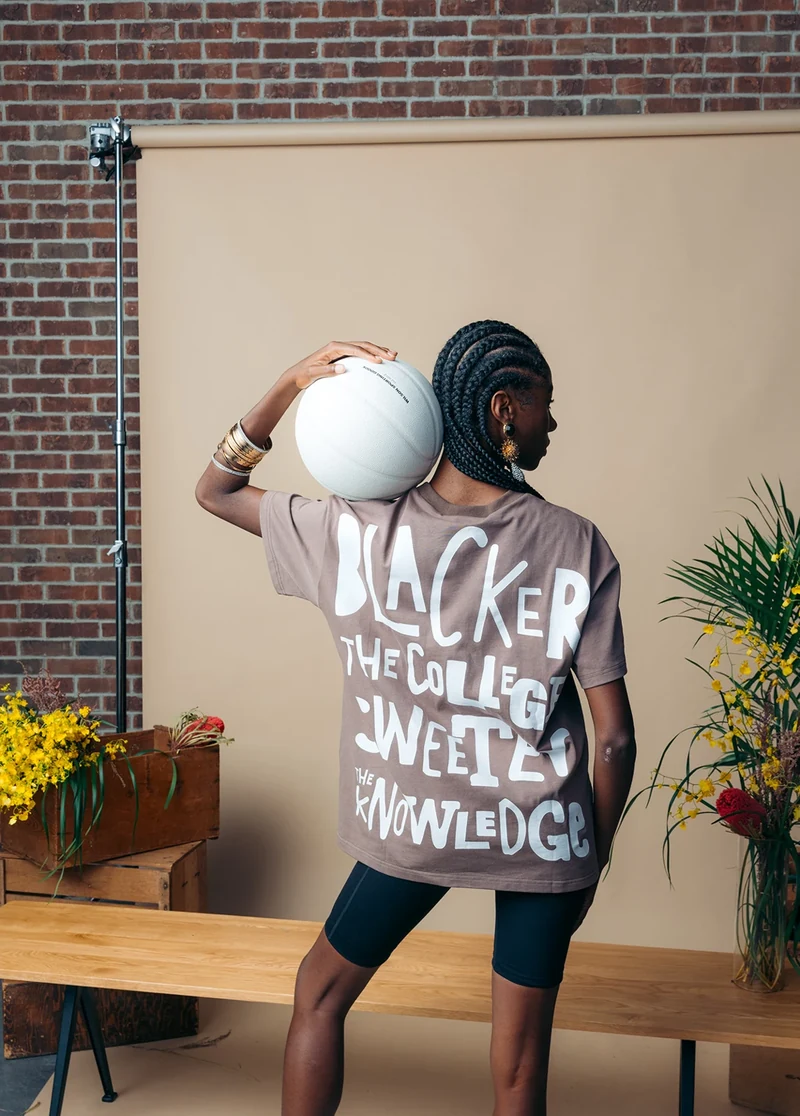 Rear view of a model holding a basketball over one shoulder.