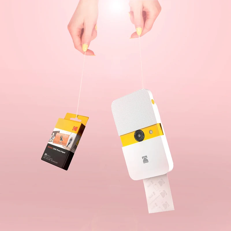 Kodak instant camera and photograph suspended against a pink backdrop.