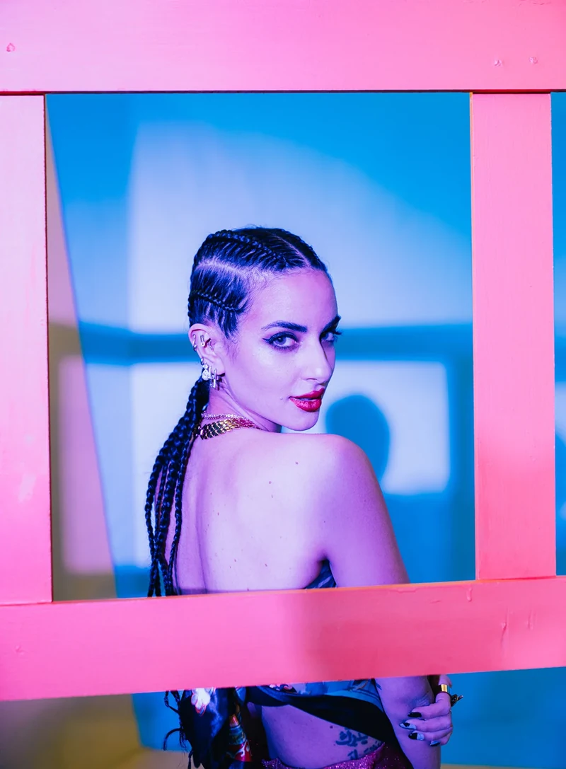 Portrait through a pink rectangular frame under colored light.