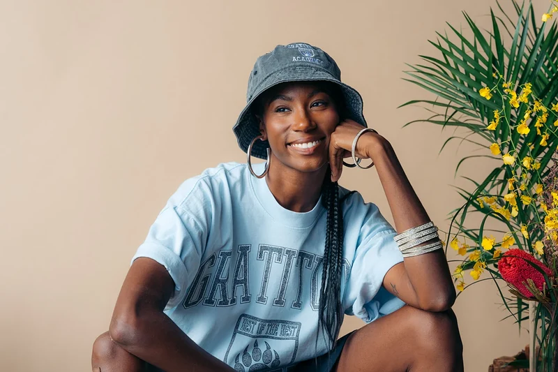 Landscape portrait of a seated model in a blue Gratitude Academy tee.