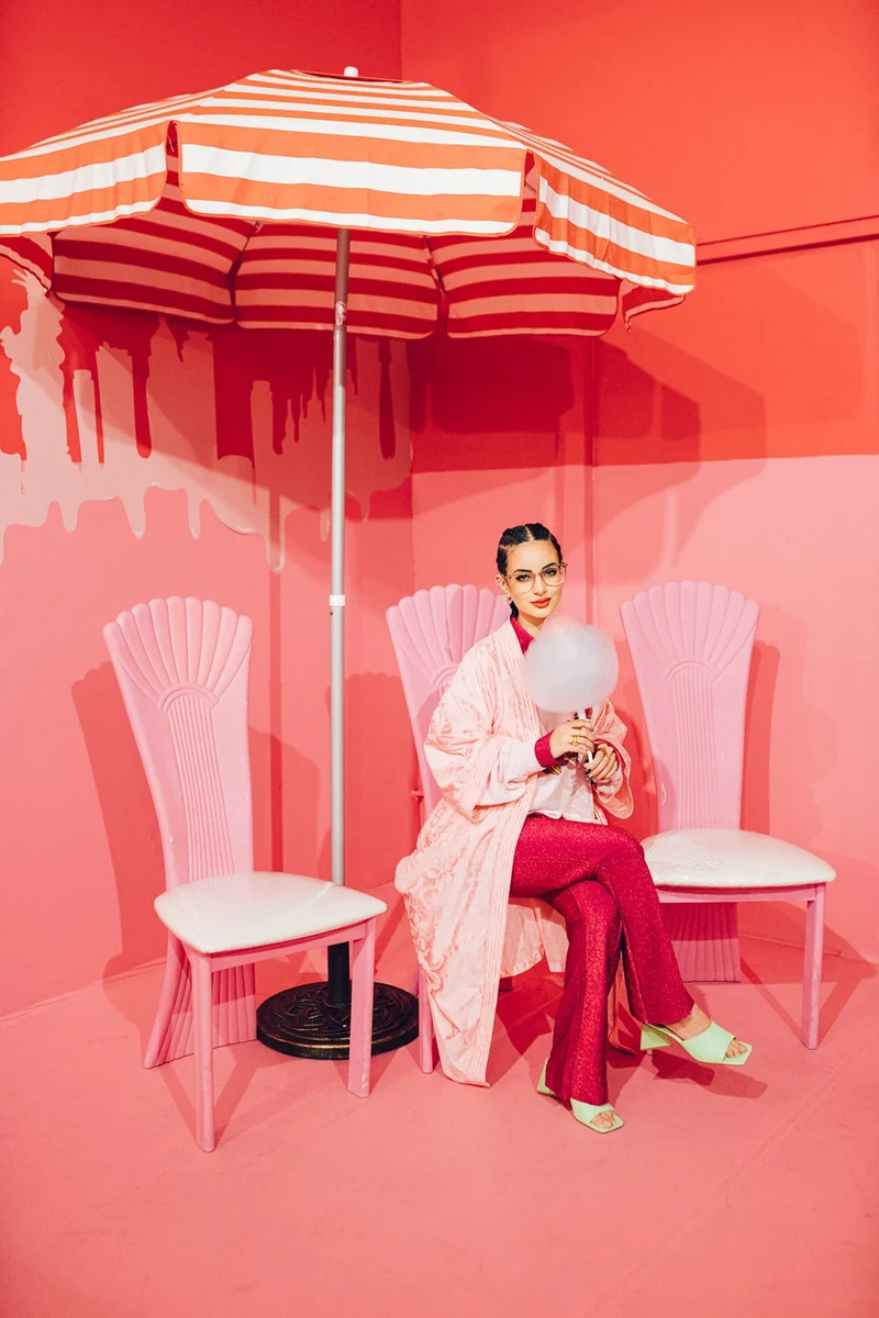 Seated fashion portrait between two chairs in the coral room.
