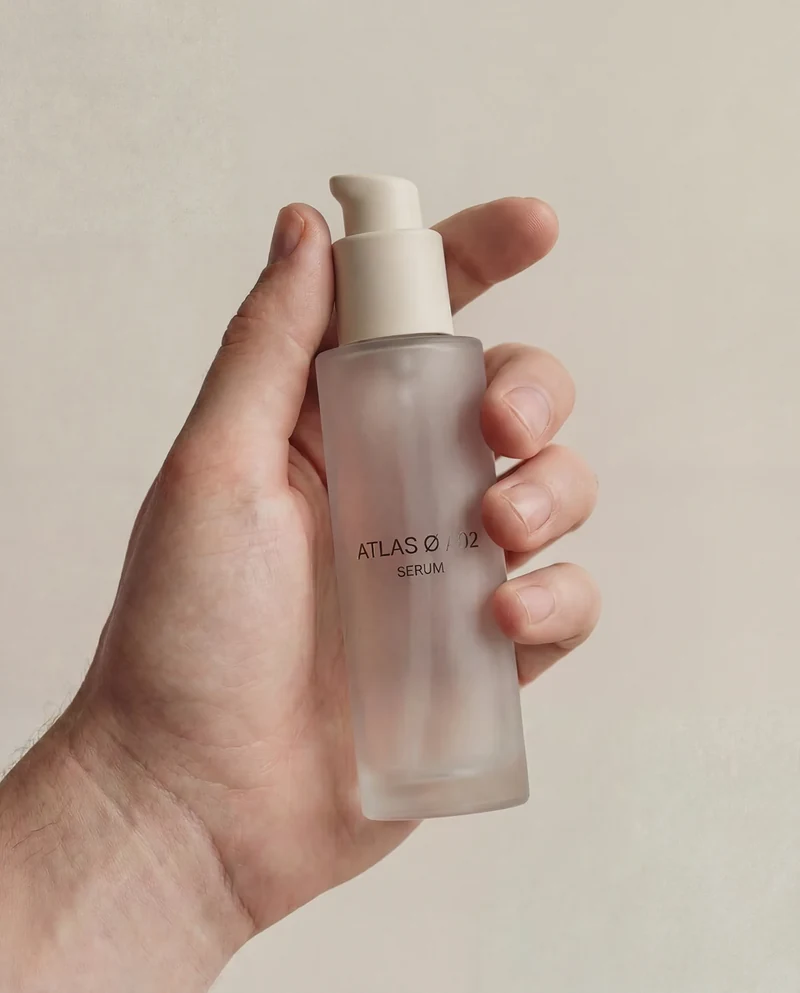 AI-generated hand holding a frosted ATLAS Ø pump bottle.