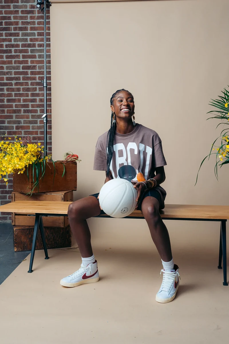 Seated model holding a white basketball on the Threaded set.