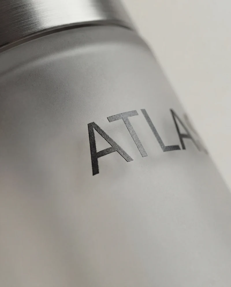 AI-generated macro view of the ATLAS Ø wordmark on a frosted bottle.