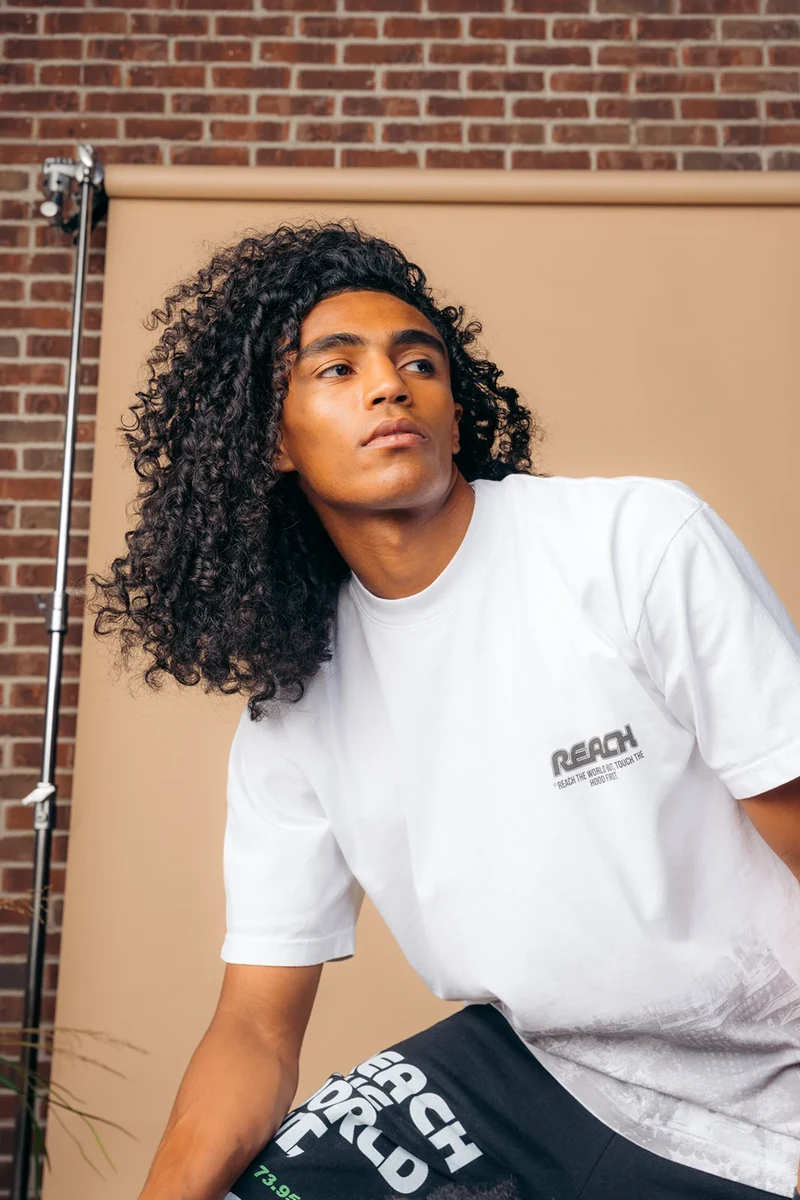 Seated model in a white tee and printed black trousers.