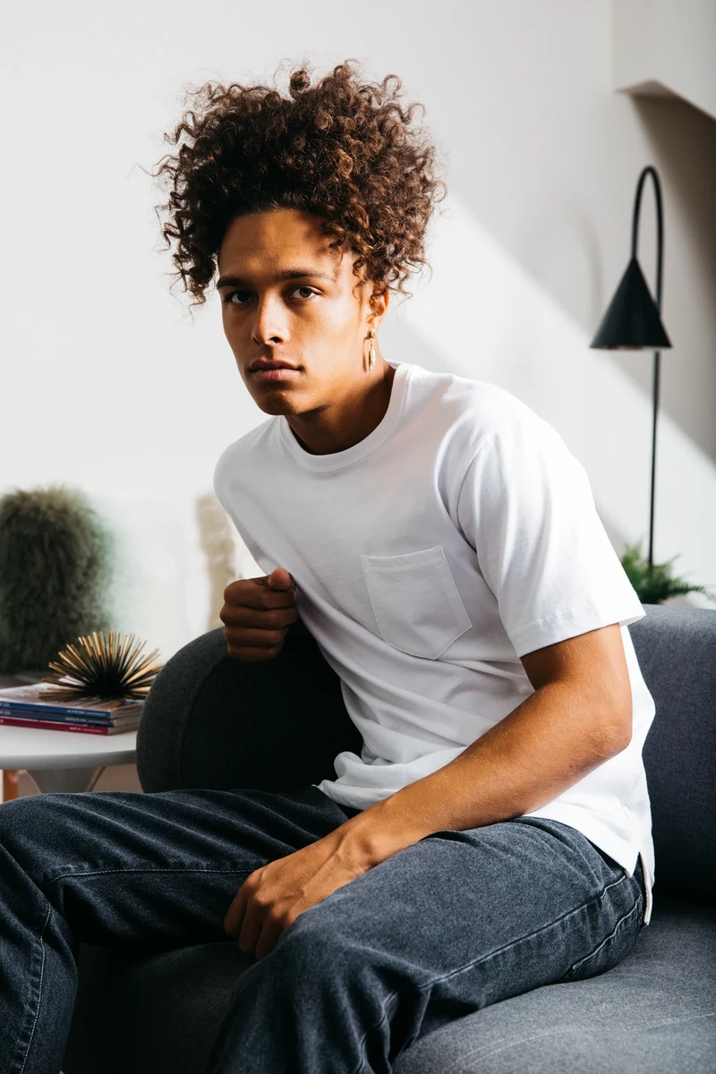 Close portrait of the model in a white tee on the couch.