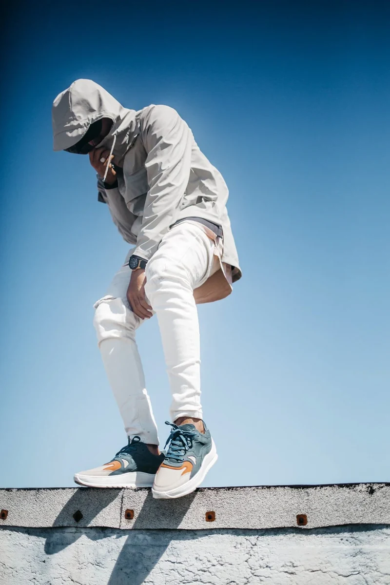 Full-length rooftop portrait emphasizing gray and orange sneakers.