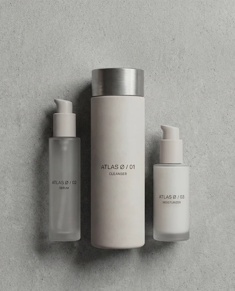 AI-generated flat lay of three ATLAS Ø bottles on concrete.