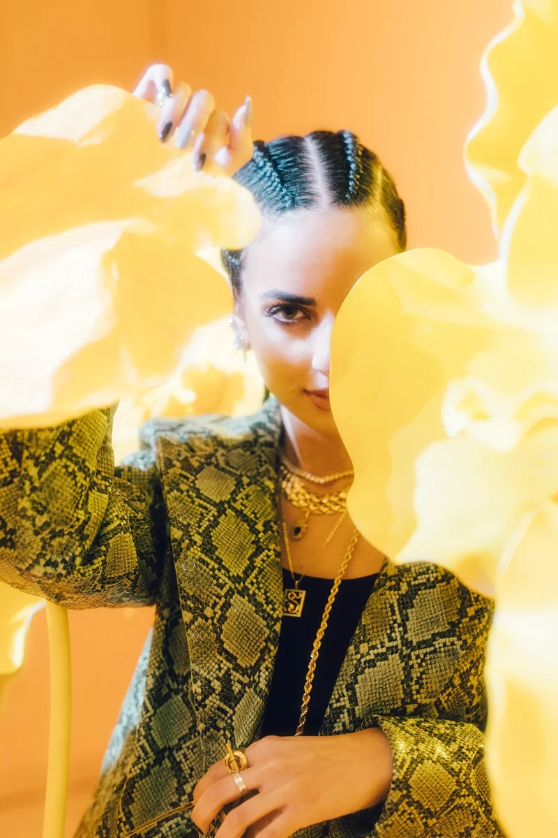 Closer portrait of ZEOPATRA through yellow hanging shapes.