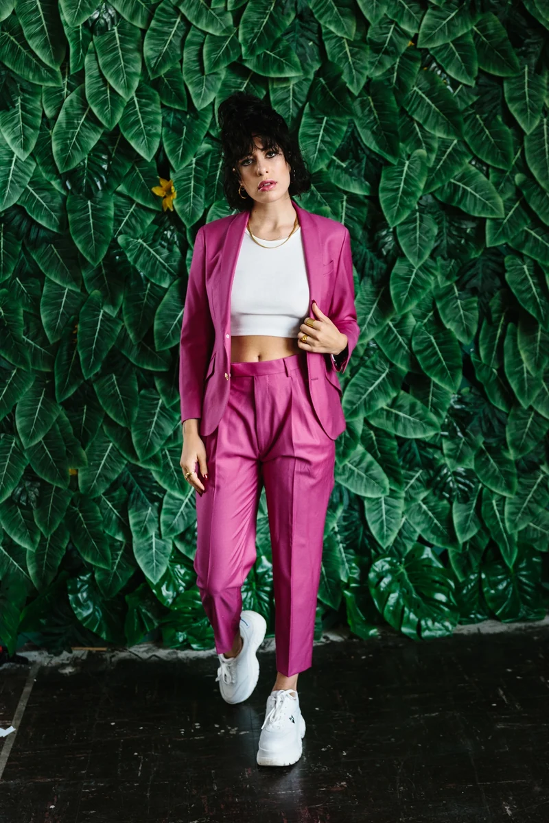 Magenta suit photographed against a green foliage wall.