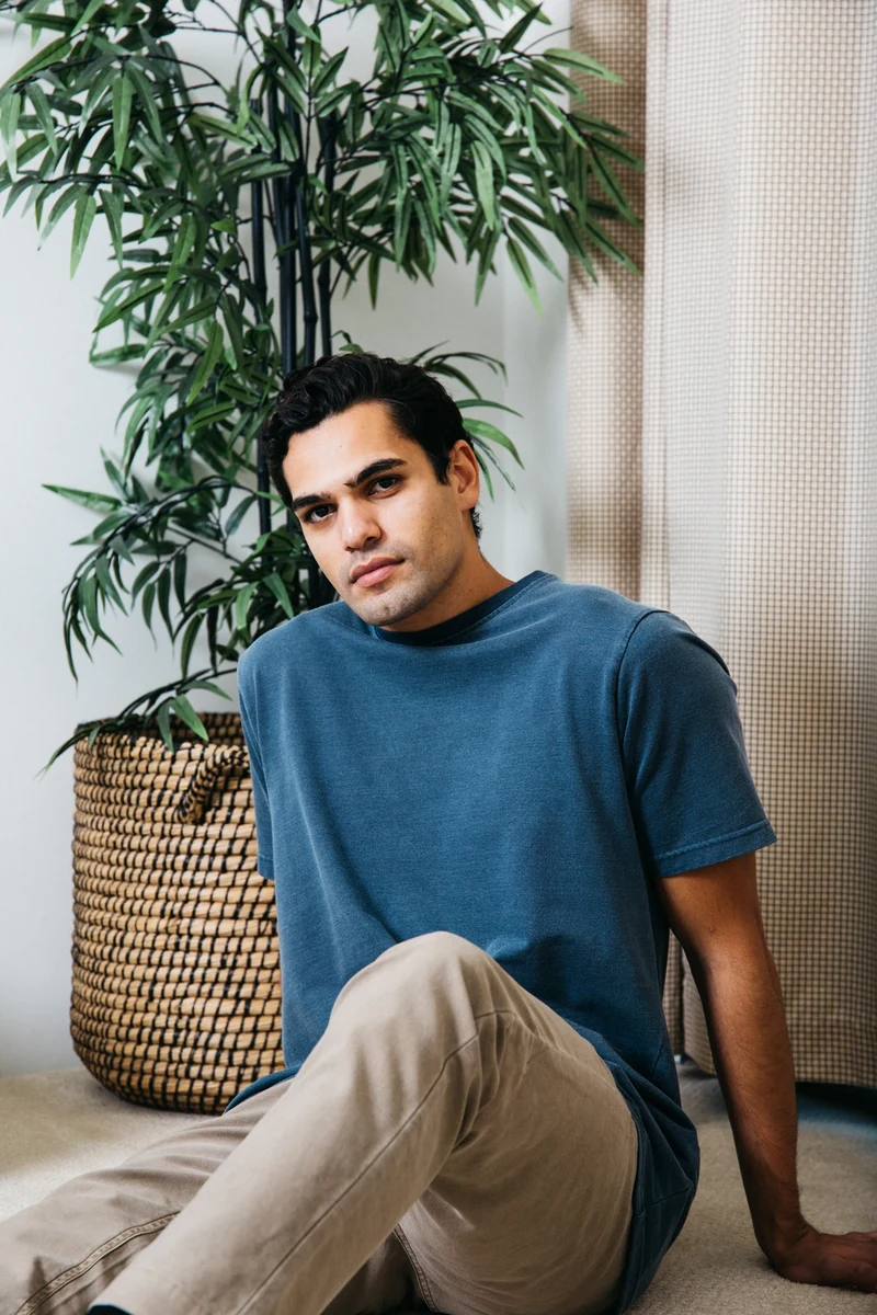 Closer seated portrait of a model in a blue tee.