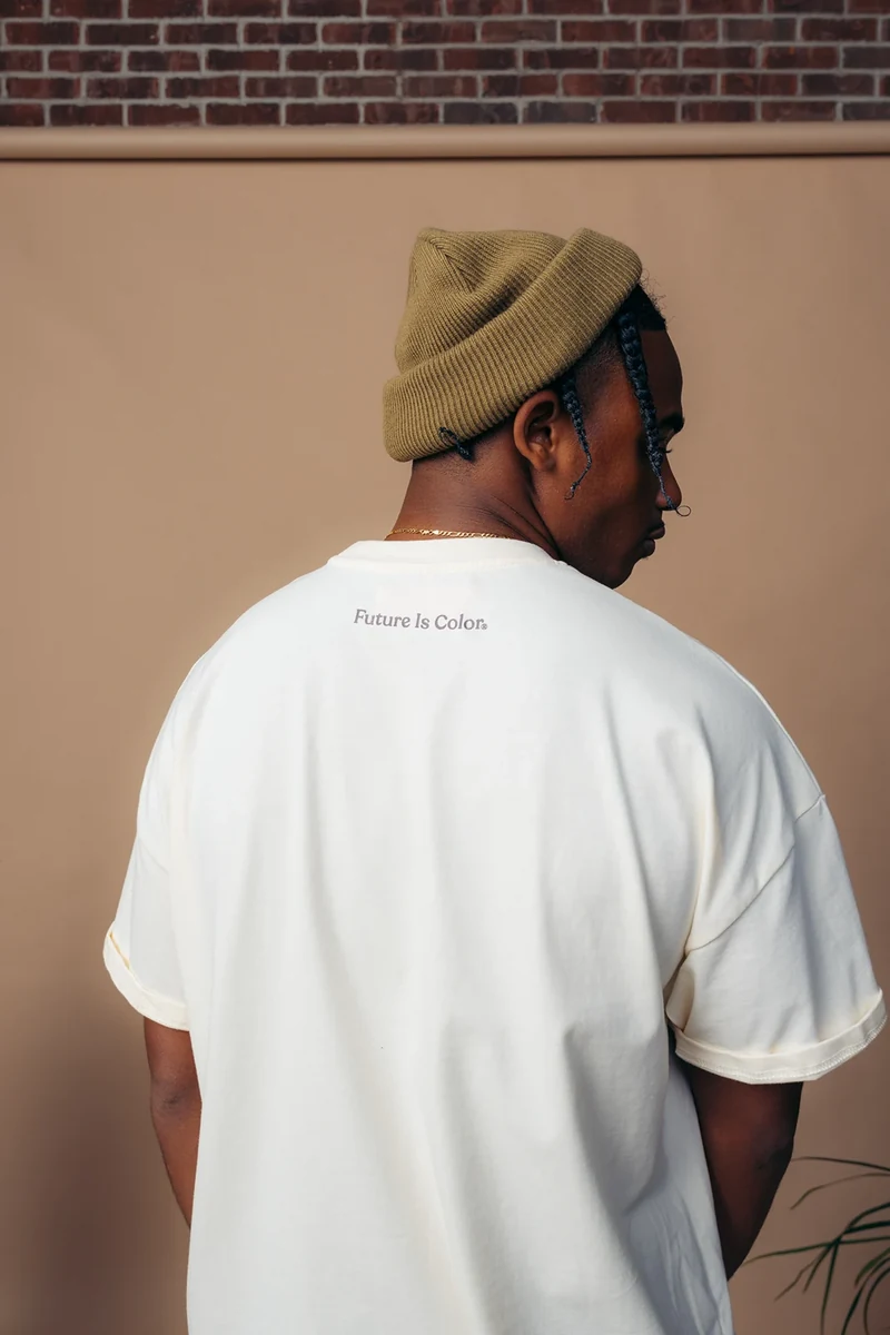 Rear three-quarter portrait of a white tee and olive knit hat.