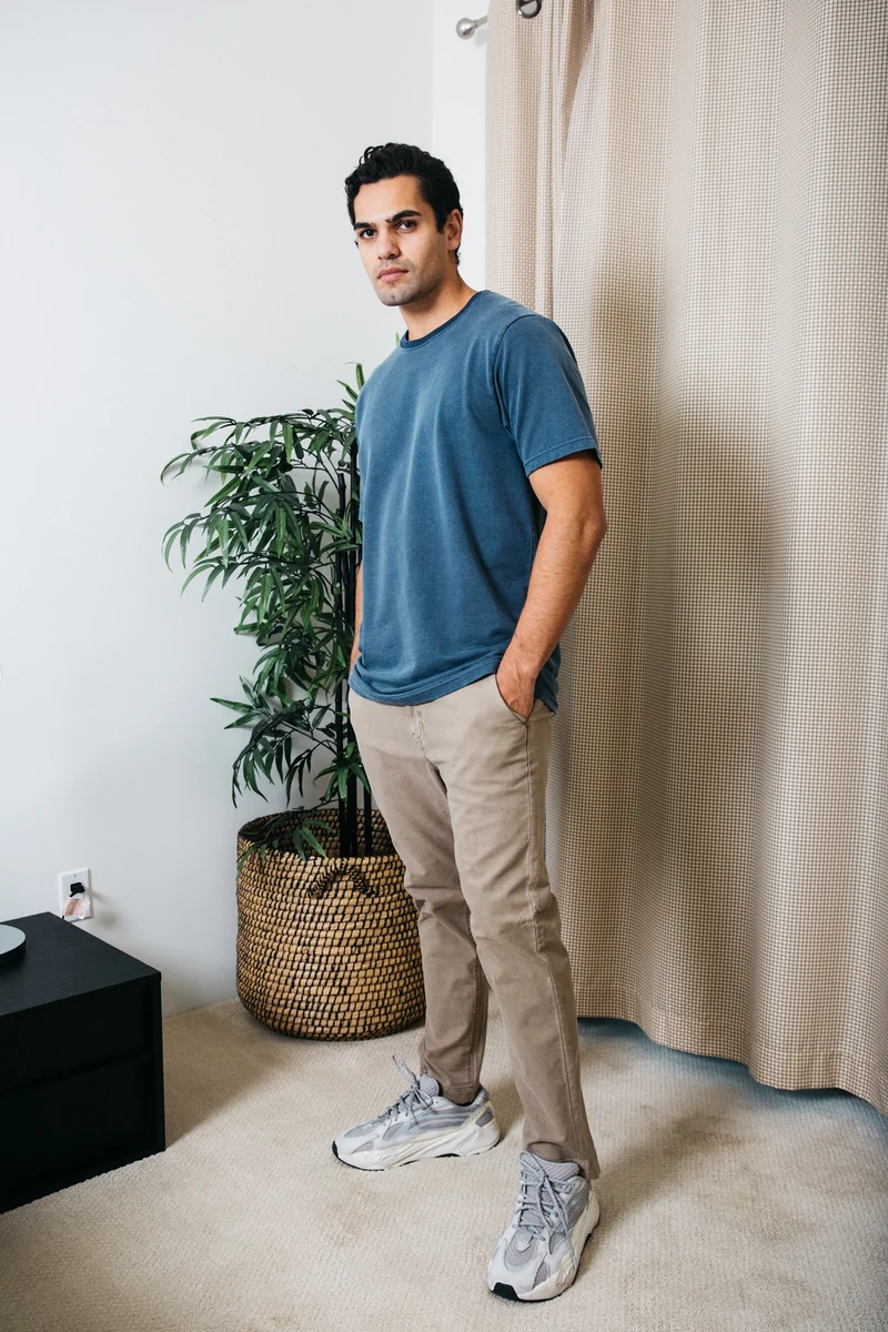 Full-length portrait in a blue tee and tan trousers.