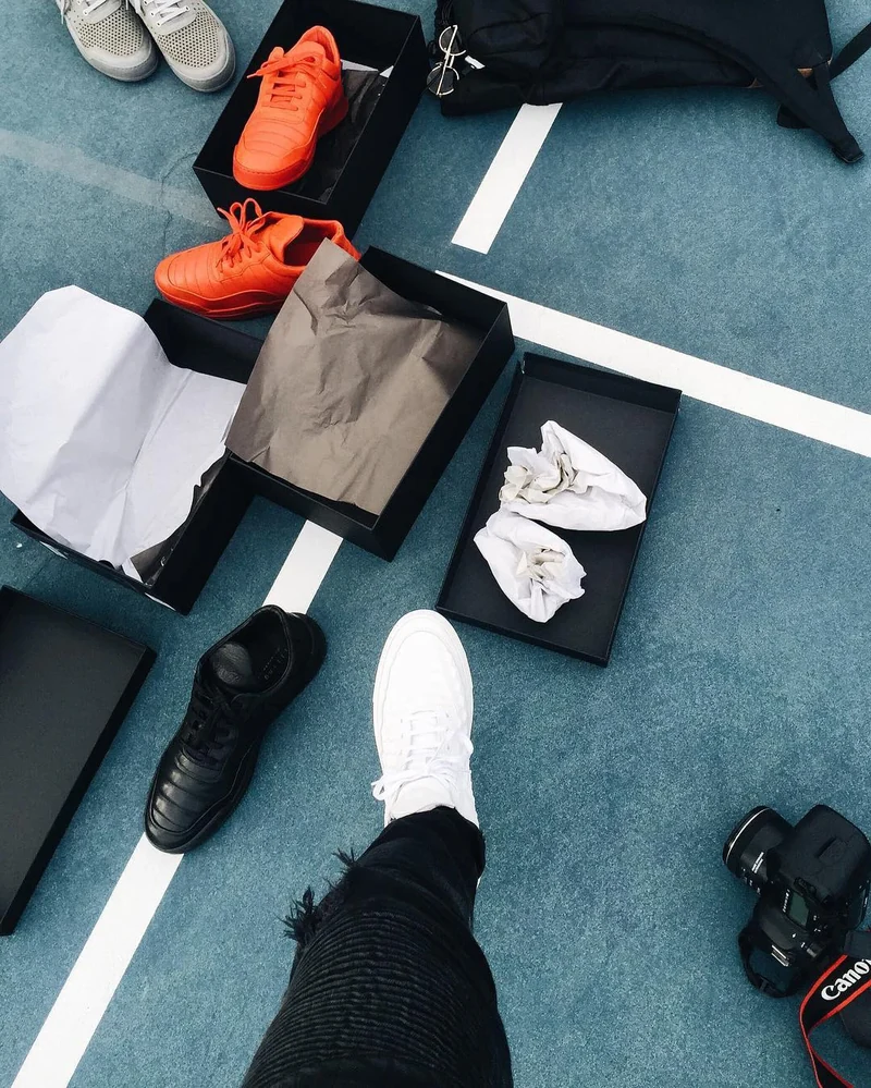 Overhead view of sneakers, clothing, and cameras on a court.