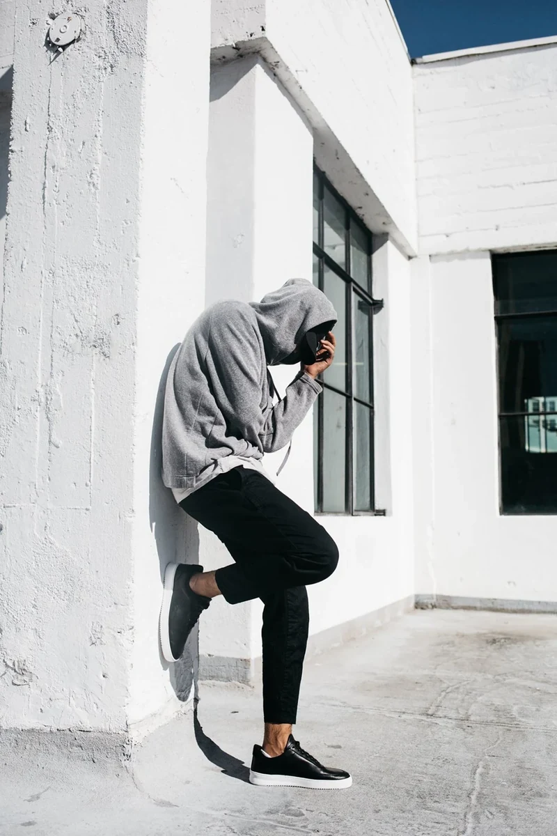Model in black sneakers stepping beside a white wall.