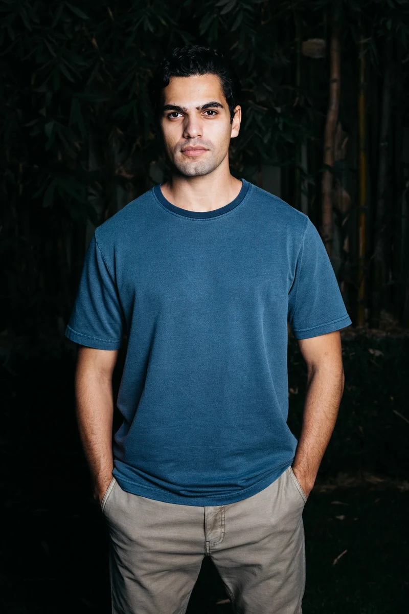 Blue tee photographed against a dark green background.