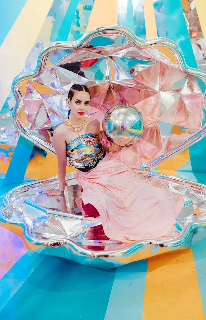 ZEOPATRA seated in a reflective shell-shaped installation.