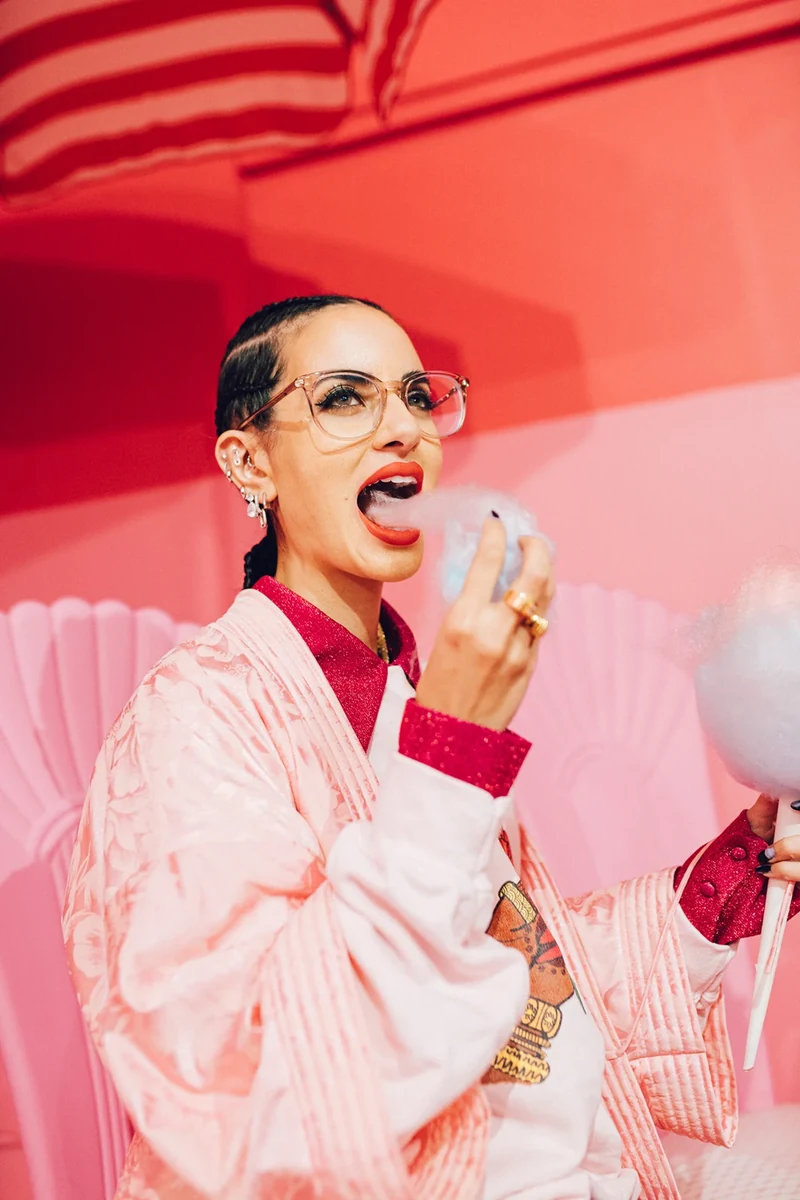 Close portrait with cotton candy beneath a striped parasol.